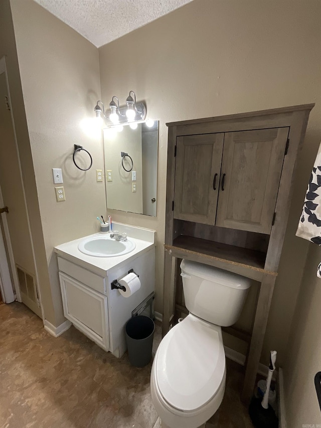 bathroom featuring vanity, a textured ceiling, and toilet