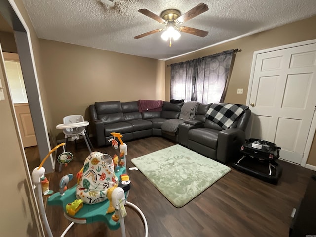 living room featuring ceiling fan, dark hardwood / wood-style flooring, and a textured ceiling