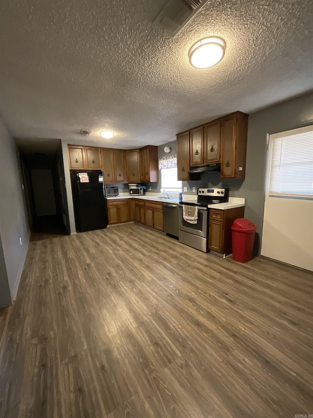 kitchen featuring sink, dark hardwood / wood-style flooring, a textured ceiling, exhaust hood, and appliances with stainless steel finishes