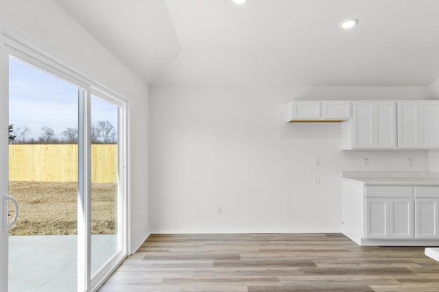 unfurnished dining area featuring light hardwood / wood-style floors and vaulted ceiling