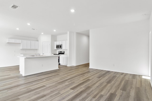 kitchen featuring a center island with sink, stainless steel appliances, white cabinets, light hardwood / wood-style floors, and sink