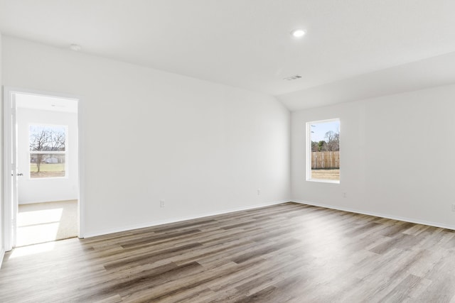 spare room with light wood-type flooring and lofted ceiling