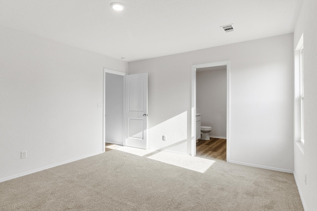 unfurnished bedroom with light carpet and connected bathroom