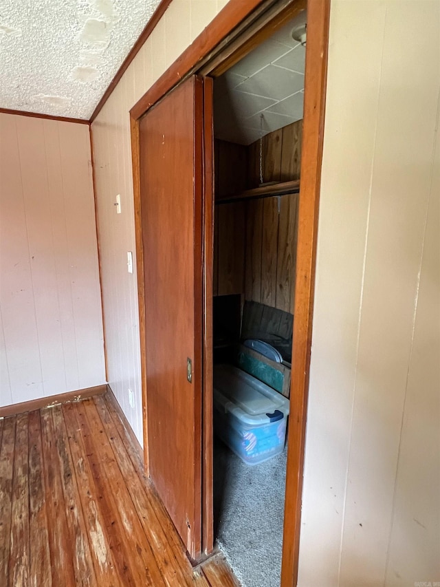 hall featuring wood walls, light hardwood / wood-style floors, and crown molding