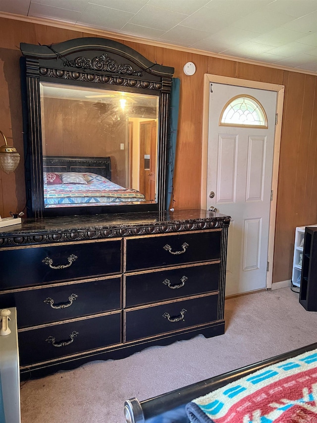 carpeted bedroom featuring wood walls and ornamental molding