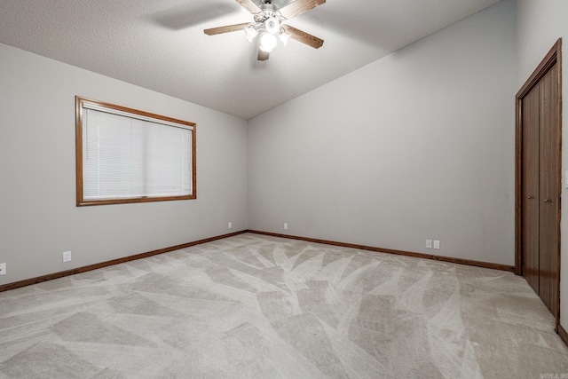 unfurnished bedroom with ceiling fan, light colored carpet, a textured ceiling, and vaulted ceiling