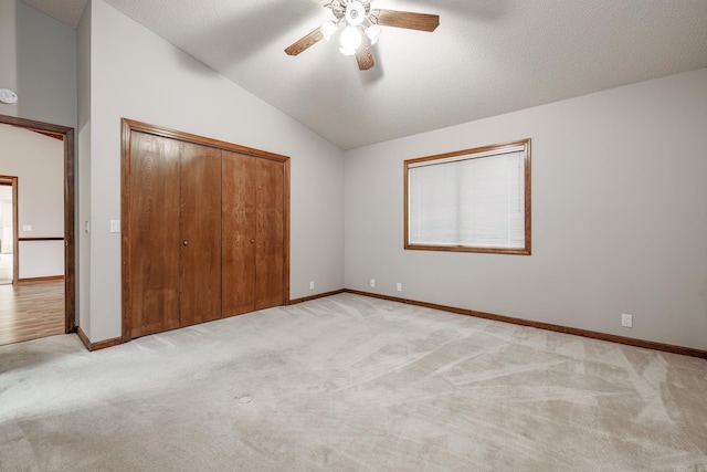 unfurnished bedroom with light carpet, a textured ceiling, ceiling fan, a closet, and lofted ceiling