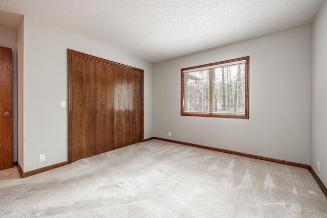 unfurnished bedroom with light colored carpet, a textured ceiling, and a closet