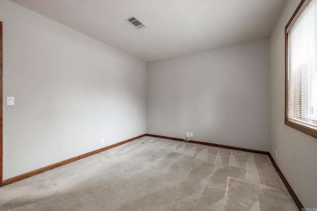 unfurnished room with light carpet and a textured ceiling