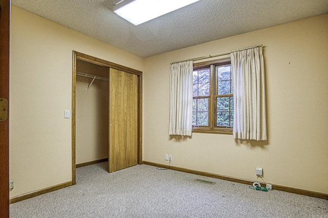 unfurnished bedroom with light carpet, a textured ceiling, and a closet