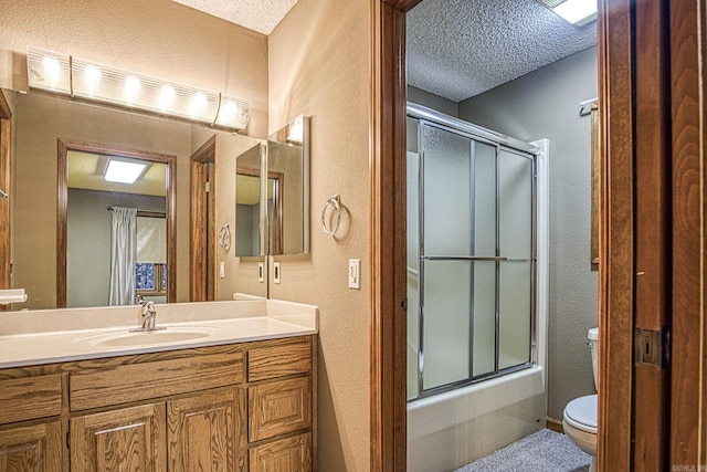 full bathroom featuring vanity, a textured ceiling, toilet, and bath / shower combo with glass door