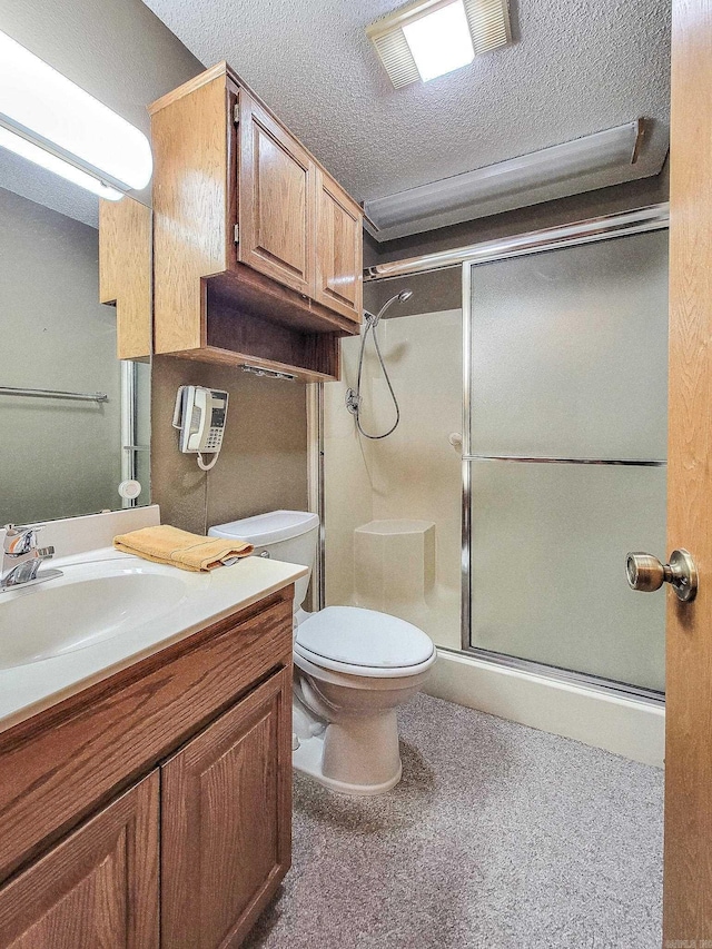 bathroom with vanity, a shower with shower door, and a textured ceiling