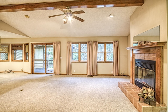 unfurnished living room featuring carpet, plenty of natural light, a textured ceiling, and a tile fireplace