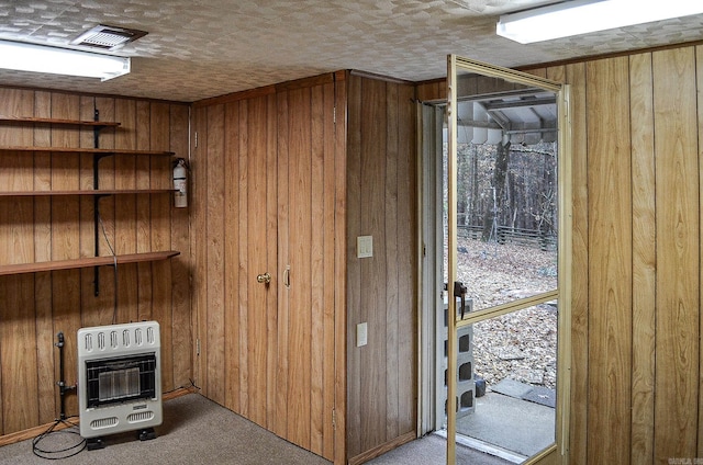 interior space featuring carpet flooring, heating unit, and wooden walls