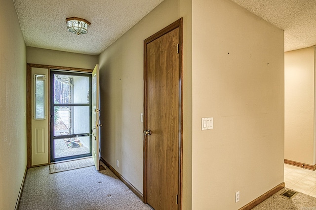 foyer entrance featuring a textured ceiling and light colored carpet