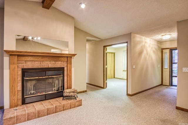 unfurnished living room with carpet, vaulted ceiling with beams, a textured ceiling, and a tiled fireplace