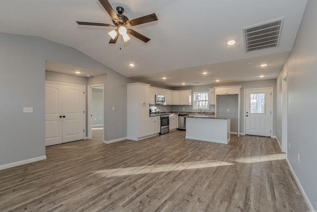 kitchen featuring a center island, vaulted ceiling, light hardwood / wood-style flooring, appliances with stainless steel finishes, and white cabinetry