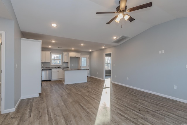 kitchen with dishwasher, white cabinets, plenty of natural light, and lofted ceiling