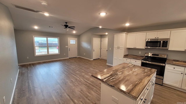 kitchen featuring a center island, vaulted ceiling, ceiling fan, appliances with stainless steel finishes, and white cabinetry