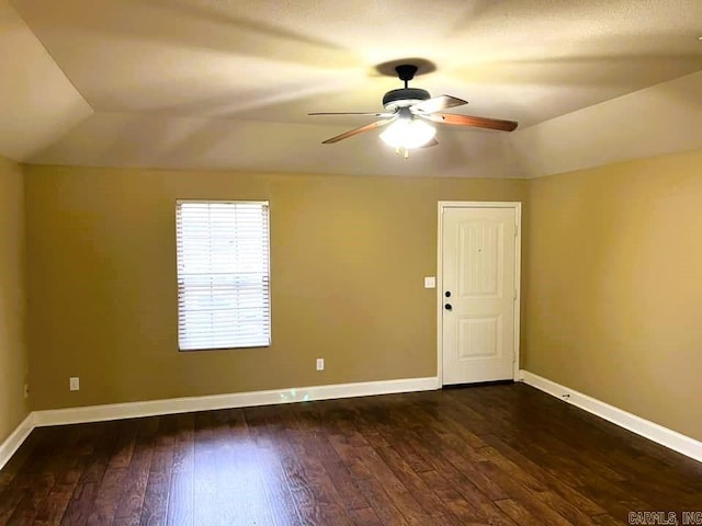 empty room with vaulted ceiling, ceiling fan, and dark wood-type flooring