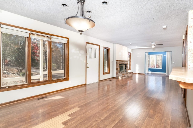 unfurnished living room with ceiling fan, a textured ceiling, and hardwood / wood-style floors