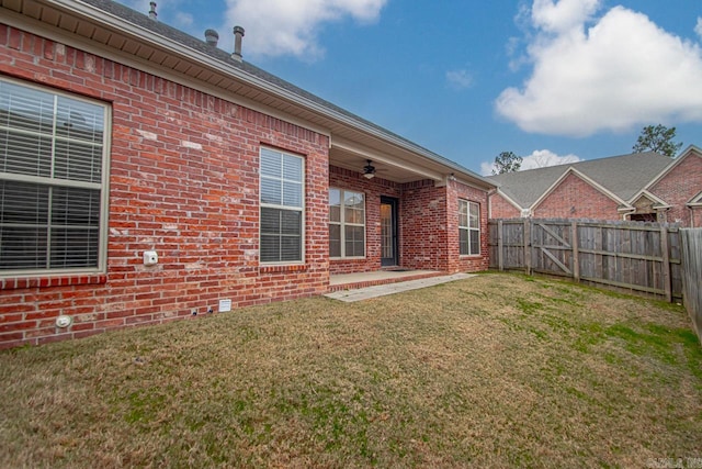 rear view of property with a lawn and ceiling fan