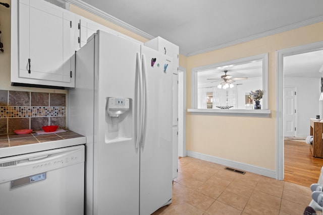 kitchen featuring white cabinetry, tile counters, crown molding, and white appliances