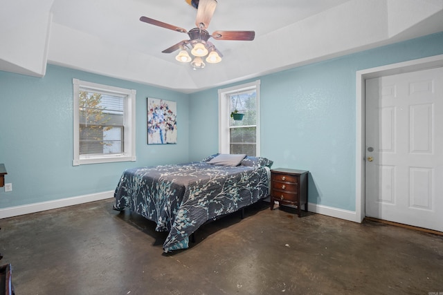 bedroom with a raised ceiling, multiple windows, and ceiling fan