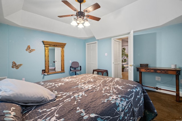 carpeted bedroom with a raised ceiling and ceiling fan