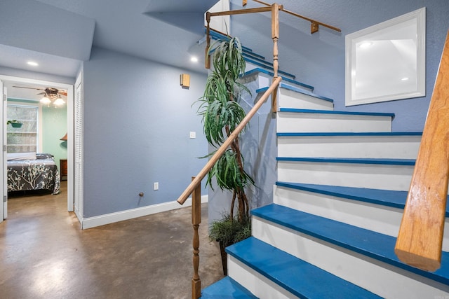 stairway with ceiling fan, a textured ceiling, and concrete floors