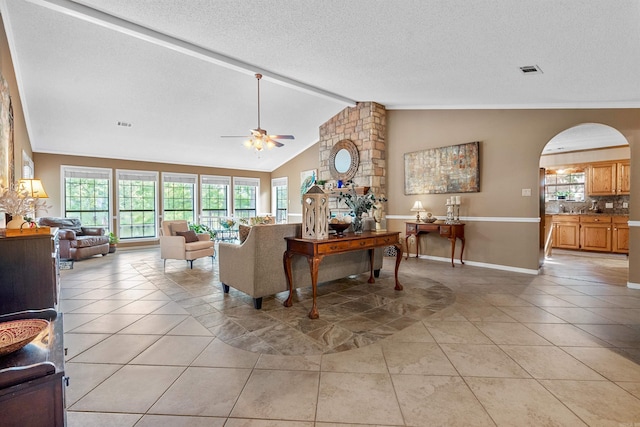 tiled living room with ceiling fan, lofted ceiling with beams, and a textured ceiling