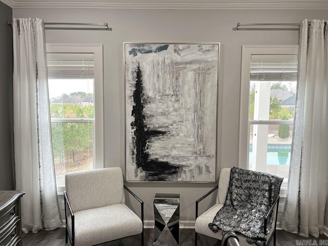 living area featuring wood-type flooring, ornamental molding, and a wealth of natural light