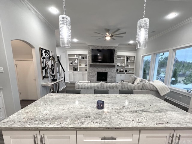 kitchen featuring pendant lighting, white cabinets, ceiling fan, light stone countertops, and a fireplace