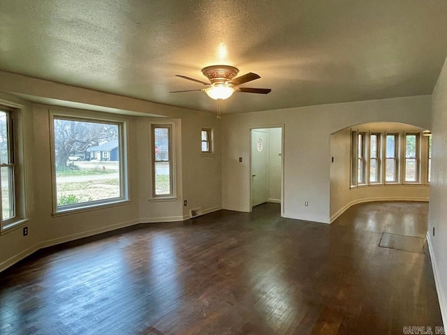 interior space with baseboards, dark wood-type flooring, and a healthy amount of sunlight