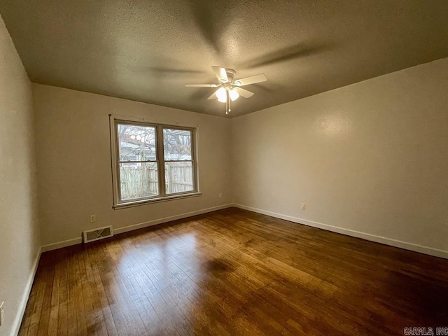 unfurnished room with ceiling fan, dark wood-type flooring, visible vents, and baseboards