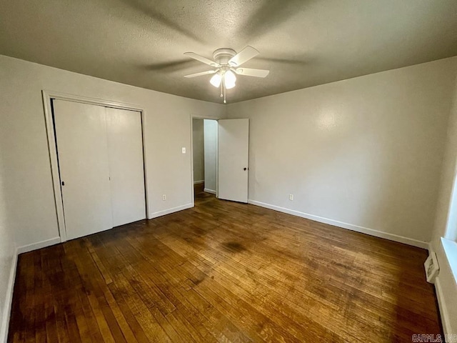 unfurnished bedroom featuring baseboards, a ceiling fan, hardwood / wood-style flooring, a textured ceiling, and a closet