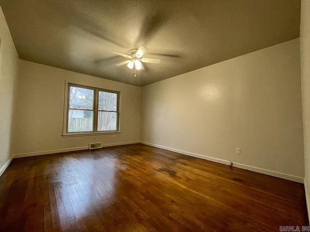 unfurnished room featuring baseboards, ceiling fan, visible vents, and dark wood-type flooring