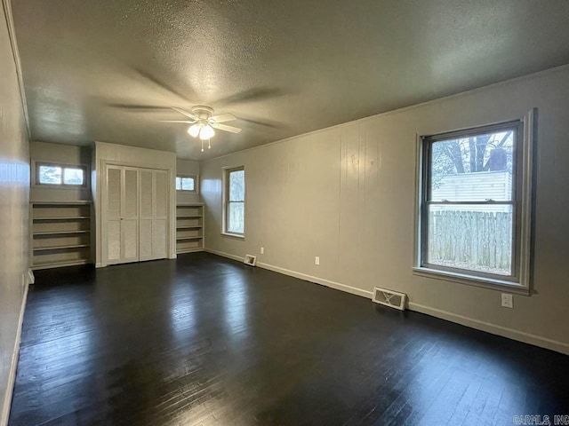 empty room with a textured ceiling, dark wood-style flooring, stairs, and visible vents