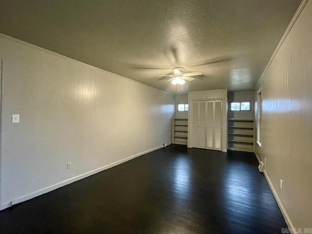 unfurnished room with ceiling fan, a textured ceiling, baseboards, stairs, and dark wood finished floors