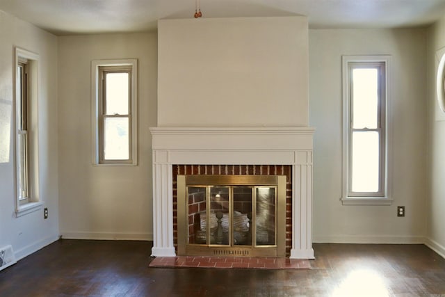 unfurnished living room featuring a brick fireplace, wood finished floors, a wealth of natural light, and baseboards