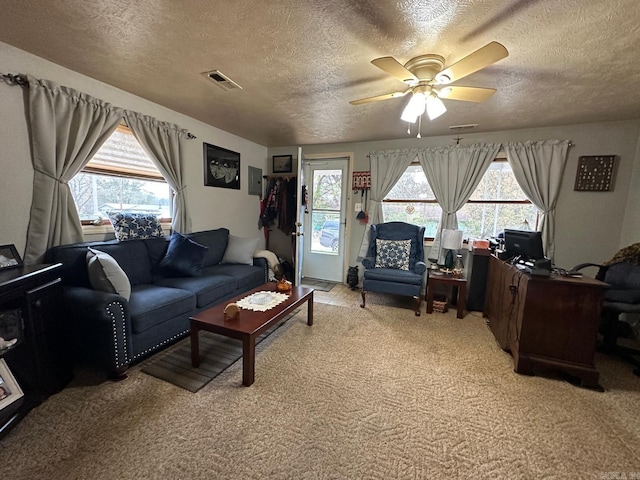 living room featuring plenty of natural light, ceiling fan, a textured ceiling, and light carpet