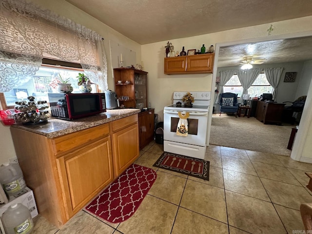 kitchen featuring ceiling fan, light tile patterned floors, a textured ceiling, and white electric range