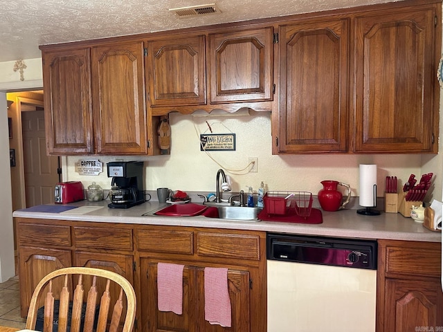 kitchen featuring tile patterned floors, dishwasher, a textured ceiling, and sink