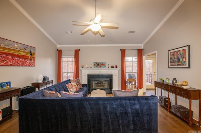 living room with crown molding, a premium fireplace, plenty of natural light, and hardwood / wood-style floors