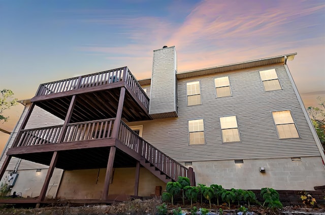 back house at dusk featuring a deck