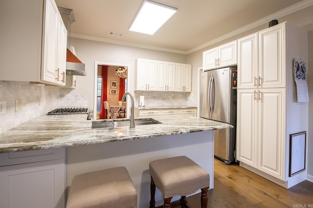 kitchen featuring kitchen peninsula, stainless steel fridge, sink, and white cabinets