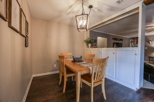 dining space featuring a chandelier, a textured ceiling, and dark wood-type flooring