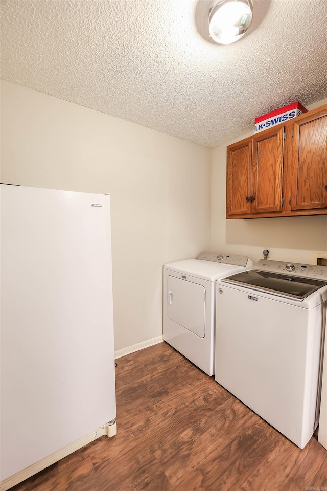 laundry room with a textured ceiling, cabinets, dark wood-type flooring, and washing machine and dryer