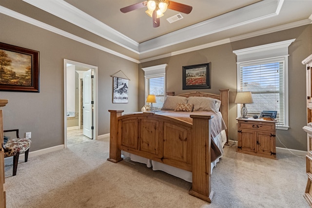 bedroom featuring light carpet, ensuite bathroom, crown molding, ceiling fan, and a tray ceiling