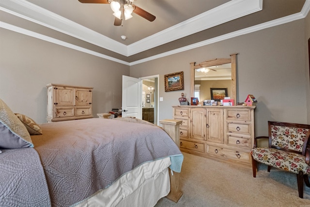 carpeted bedroom with a raised ceiling, connected bathroom, ceiling fan, and ornamental molding